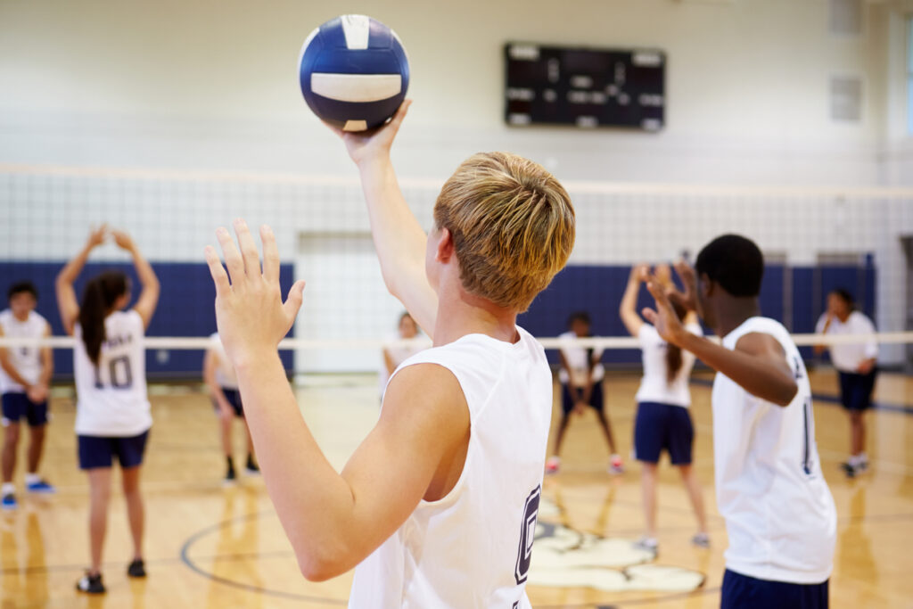High School Volleyball Match In Gymnasium Holding Ball