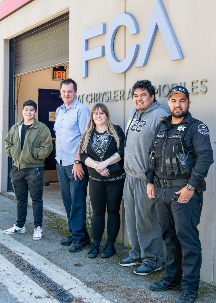 Instructor Amber Avery-Graff, her students and a member of the Shoreline Police Department stand outside Shoreline's automotive department.