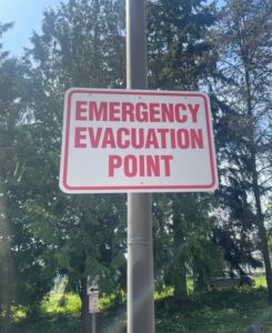 This is an image of our emergency evacuation point signs.  These are white signs with red writing.