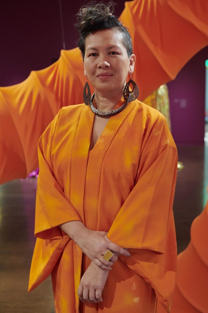 This s an image of a woman in an orange robe again a purple and orange background