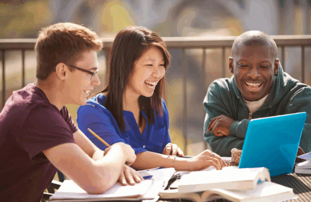 Three people working on a laptop computer.